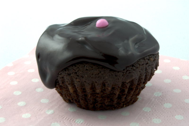 Deep Chocolate Brownie Cupcake A close up photo of a chocolate brownie cupcake with a pink ball on a pink napkin.
