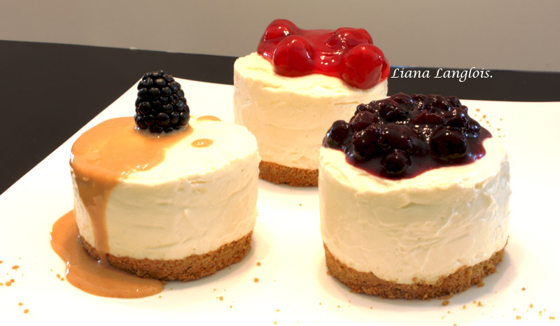 Cheesecake A close up photo of 3 individual cheesecake desserts, one with blueberry sauce, one with cherry topping and one with dulce de leche sauce and a blackberry.