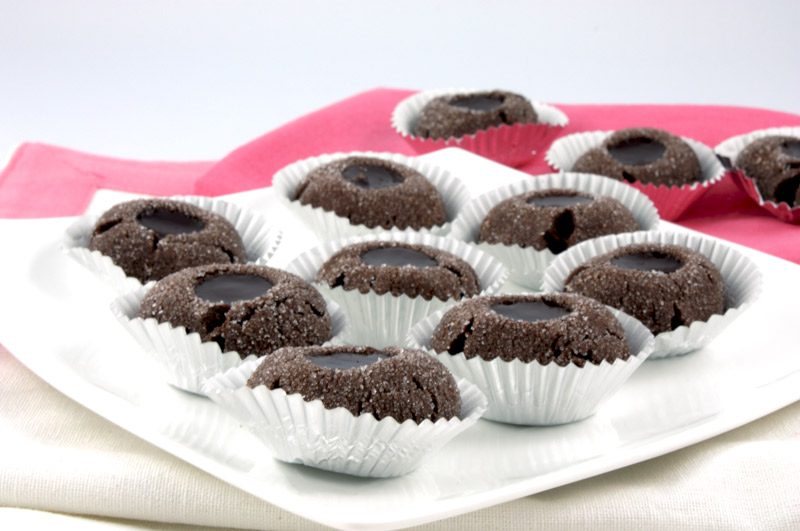 Chocolate Thumbprints A close up photo of chocolate thumbprints on a white plate with a pink napkin.