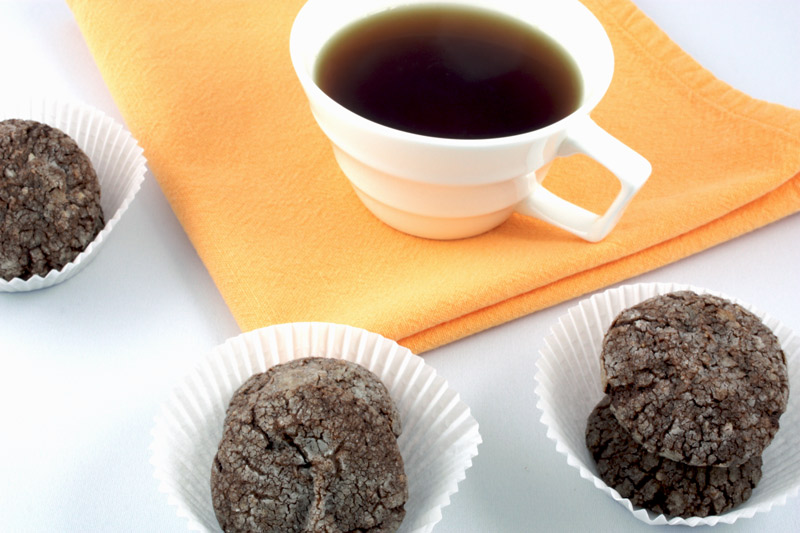 Dark Chocolate-Almond Crackles A photo of dark chocolate-almond crackles in 3 white paper cups with a white cup of tea on an orange napkin.