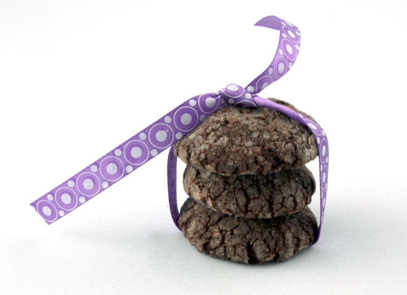 Dark Chocolate-Almond Crackles A close up photo of 3 dark chocolate-almond crackles tied in a purple ribbon.