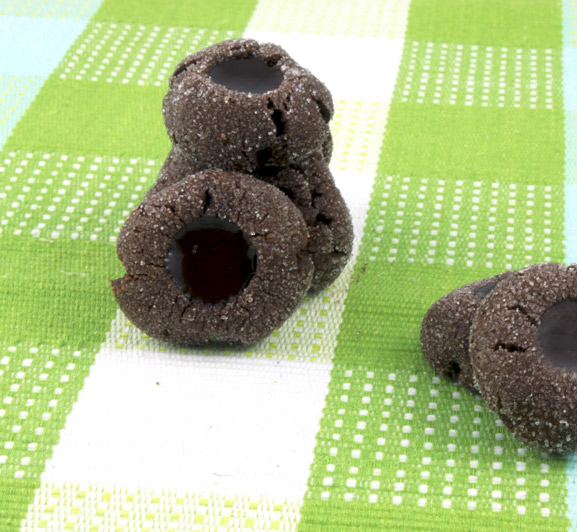 Chocolate Thumbprints A photo of stacked chocolate thumbprints on a green patterned placemat.