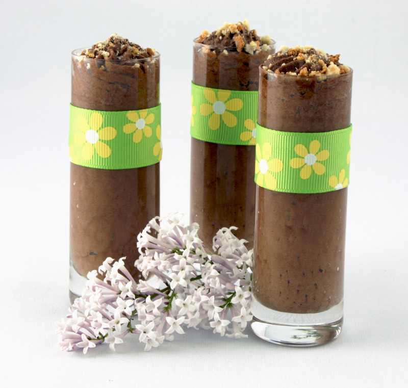 Gordon Ramsay Four-Minute Chocolate Mousse A photo of three individual chocolate mousse desserts in shot glasses with a green and yellow ribbon and a sprig of lilac.