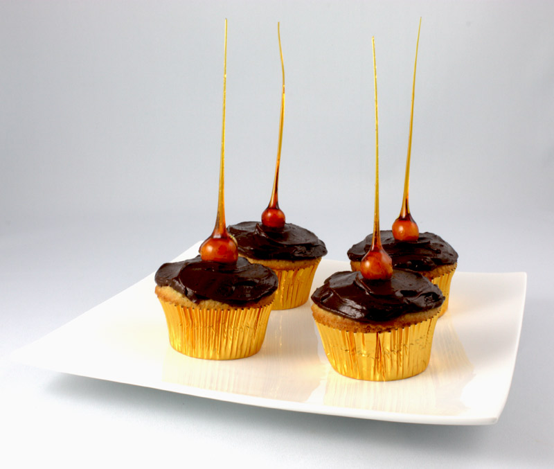 Candied-Hazelnut Cupcakes A close up photo of 4 candied-hazelnut cupcakes on a white plate.