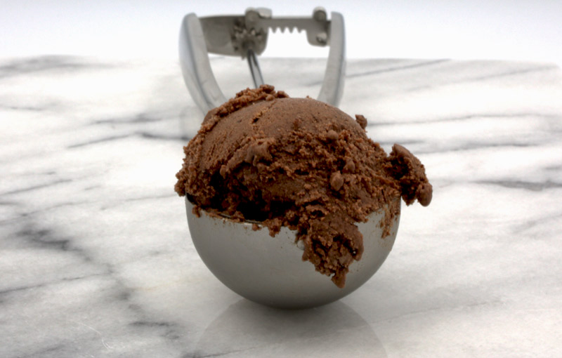 Ben & Jerry's Chocolate Ice Cream A photo of a scoop of chocolate ice cream in a silver ice cream scoop dispenser on a marble slab.