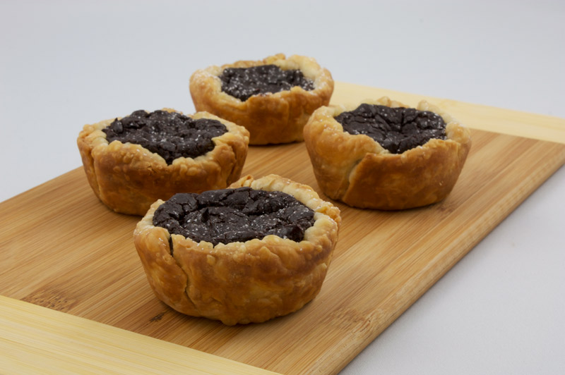 Chocolate Custard Tartlettes A photo of 4 chocolate custard tartlettes on a wooden cutting board.