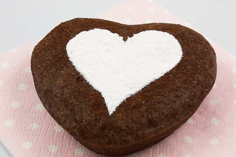 chocolate brownie hearts, brownie hearts, Martha Stewart's brownie hearts, recipe for brownie hearts A close up photo of 1 chocolate brownie heart decorated with icing sugar in the shape of a heart placed on a pink polka dot napkin.
