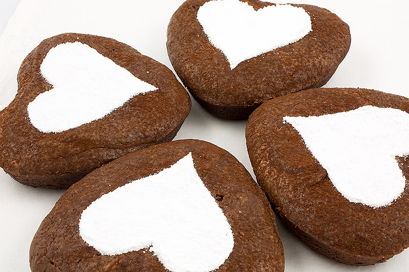 chocolate brownie hearts, brownie hearts, Martha Stewart's brownie hearts, recipe for brownie hearts A close up photo of 4 brownie hearts decorated using a stencil in the shape of a heart and dusted with confectioners' sugar.