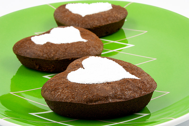 brownie hearts, chocolate brownie hearts, Martha Stewart's brownie hearts recipe, recipe for Martha Stewarts brownie hearts A close up photo with 3 chocolate brownie hearts decorated with confectioners' sugar arranged on a bright green dish.