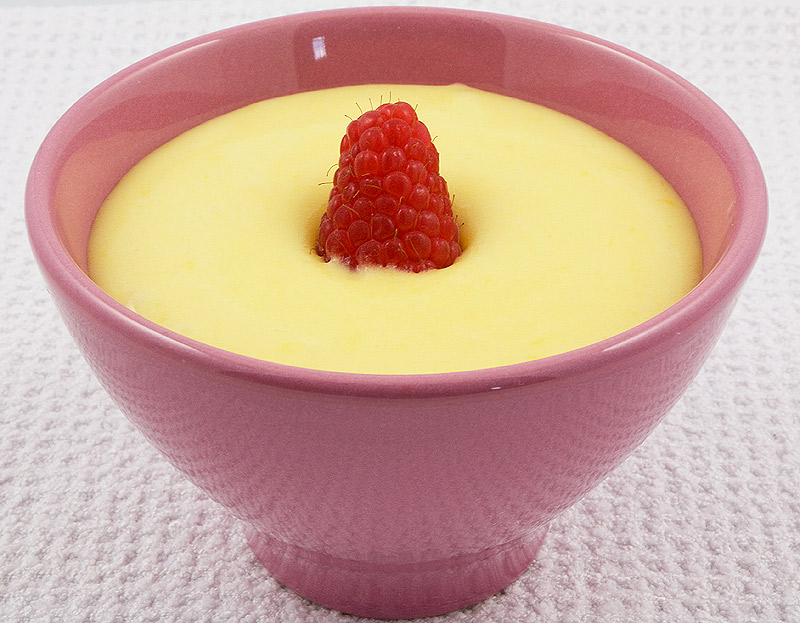 lemon curd meringue nests, meringue nests, meringue cups, easy lemon curd A photo of lemon curd in a pink bowl garnished with a raspberry.