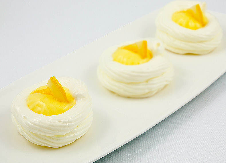 lemon curd meringue nests, meringue nests, meringue cups, easy lemon curd A photo of 3 lemon curd meringue nests garnished with candied lemon slices on a white plate.