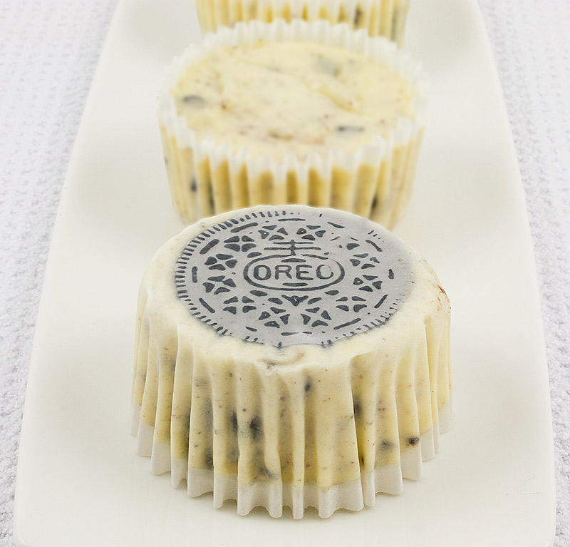 Oreo cookies and cream cheesecakes, Martha Stewart's cookies and cream cheesecakes recipe, easy recipe for Oreo cookies and cream cheesecake cupcakes A photo of 3 Oreo cookies and cream cheesecakes on a white plate, 1 with Oreo cookie side up.