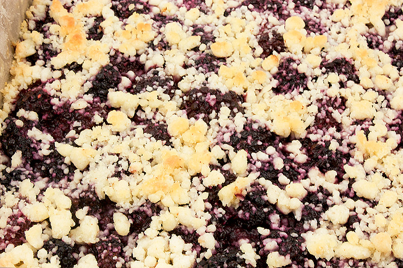 easy recipe for berry crumb bars, easy recipe for blackberry-almond shortbread squares, easy summer desserts, easy summer berry desserts A close up photo of a pan of blackberry-almond shortbread dessert in a baking pan.