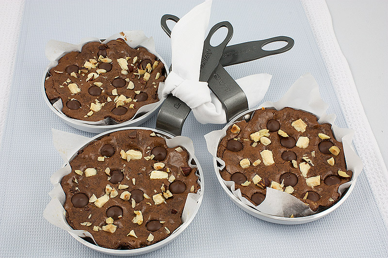 recipe for sinfully delicious brownies, decadent brownies recipe, David Lebovitz's brownie recipe, Robert's absolute best brownies recipe A photo of 3 Robert's Absolute Best Brownies in small skillets lined with parchment paper placed on a light blue table runner.