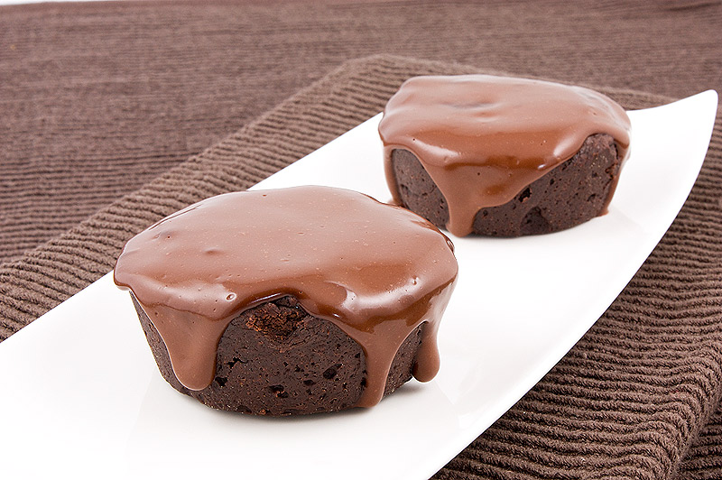 Donna Hay's Modern Classics Book 2 dessert recipes, how to make sugared berries, simple chocolate glaze recipe A photo of 2 flourless chocolate cakes with chocolate glaze on a white, rectangular plate placed on a chocolate brown tea towel.