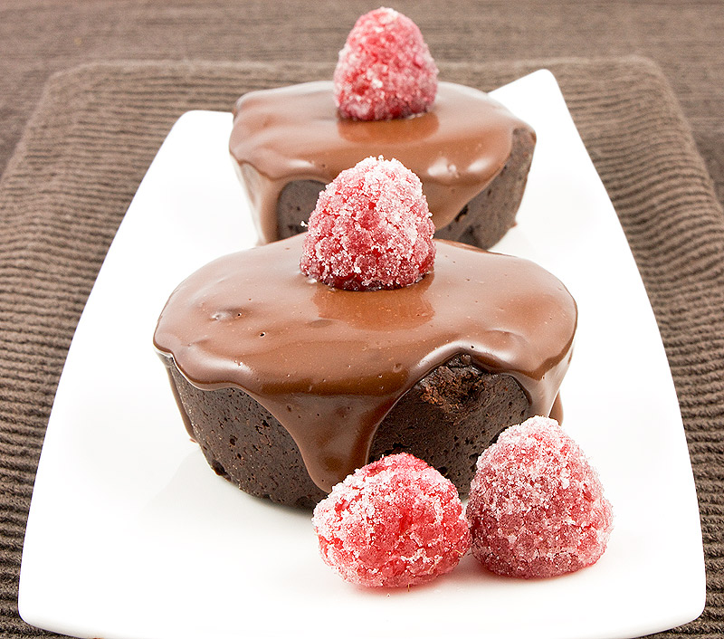 easy flourless chocolate cake recipe, simple flourless chocolate cake recipe, Donna Hay's recipe for Flourless Chocolate Cake A photo of 2 flourless chocolate cakes with chocolate glaze, garnished with sugared raspberries on a white rectangular plate placed on a chocolate brown tea towel.