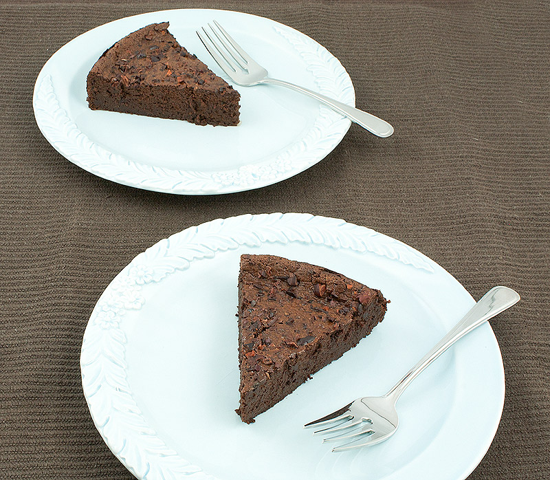 simple dessert recipes, flourless cake recipe, easy chocolate cake recipes A photo taken looking down on 2 blue plates each with a slice of flourless chocolate cake and a dessert fork.