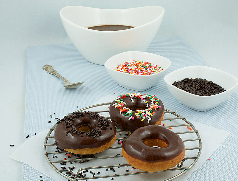 doughnut holes, Donna Hay recipes, yeast doughnut recipe A photo of chocolate glazed doughnuts mise en place consisting of chocolate doughnut glaze, chocolate sprinkles, and multi coloured sprinkles with a spoon and 3 chocolate glazed donuts on a wire rack.