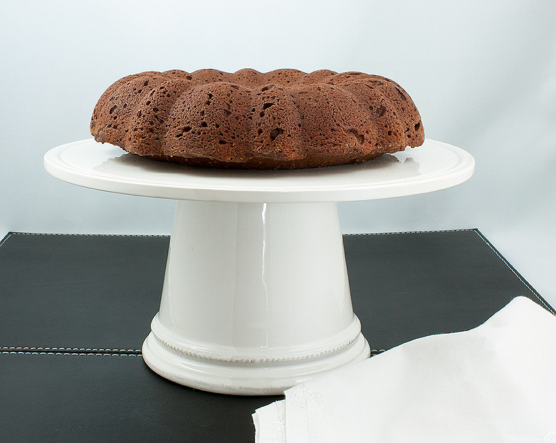 Donna Hay's Chocolate Bundt Cake with Butterscotch Cocoa Glaze A photo of Donna Hay's Chocolate Bundt Cake displayed on a white cake stand.