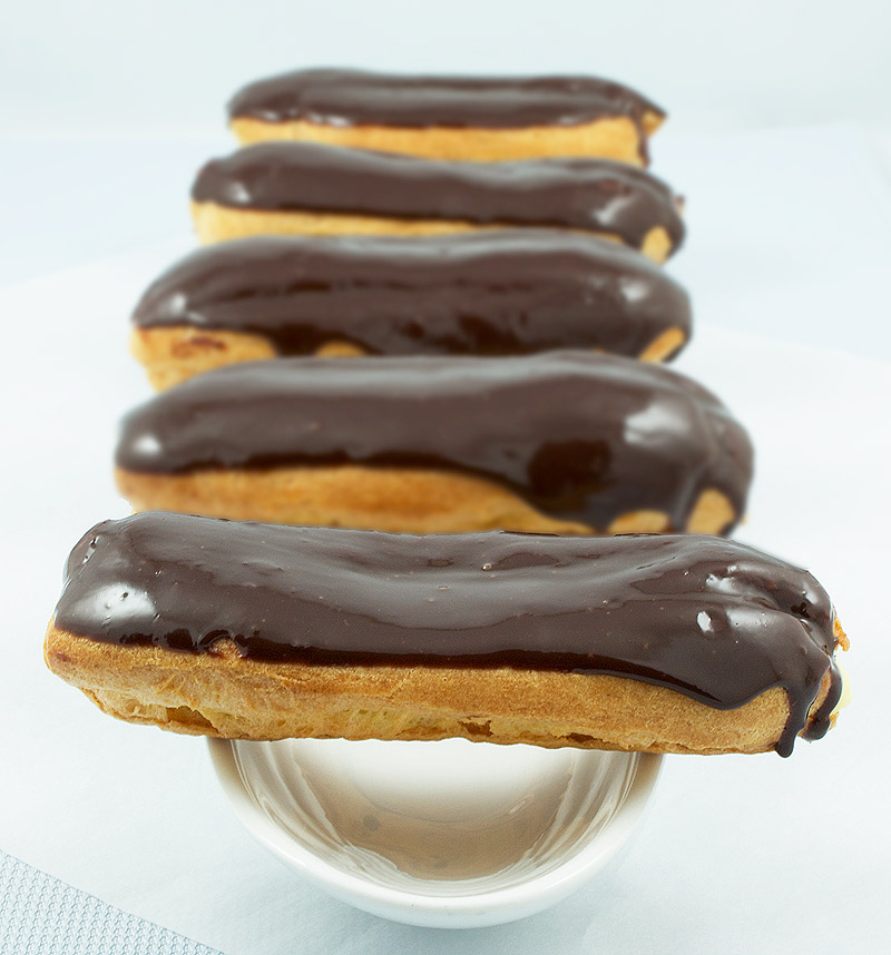 chocolate eclair dessert, chocolate eclair recipe, quick and easy chocolate desserts A photo of Chocolate Éclairs with Vanilla Bean Crème Pâtissière and Chocolate Ganache Glaze french pastries placed in a row on a long, rectangular white dish.