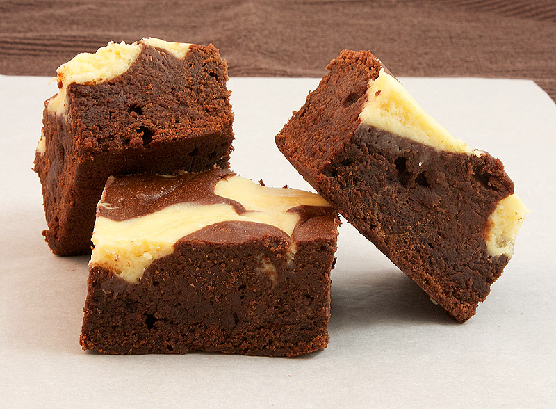 cream cheese brownies, double chocolate brownies, chocolate fudge brownie recipe A photo of 3 Baileys® Cheesecake Swirl Chocolate Brownie squares on a piece of non-stick baking paper.