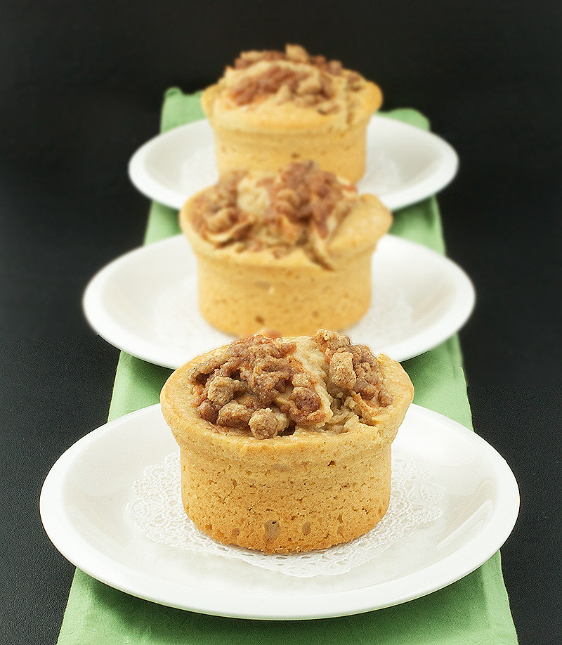 Warm Apple Cinnamon Crumb Cakes with Calvados A photo of Warm Apple Cinnamon Crumb Cakes with Calvados placed in a row on white dessert dishes.