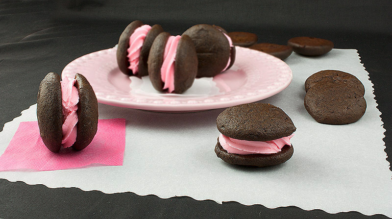 whoopie pie filling recipe, wicked whoopies, whoopie pies filling A photo of Chocolate Whoopie Pies with Vanilla Swiss Meringue Buttercream arranged on a pink plate.