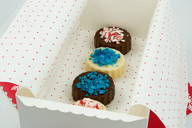 Holiday Fudge A close up photo taken looking down on a selection of Holiday Fudge - Chocolate Marshmallow Fudge and White Chocolate Fudge in a white box lined with holiday tissue paper.