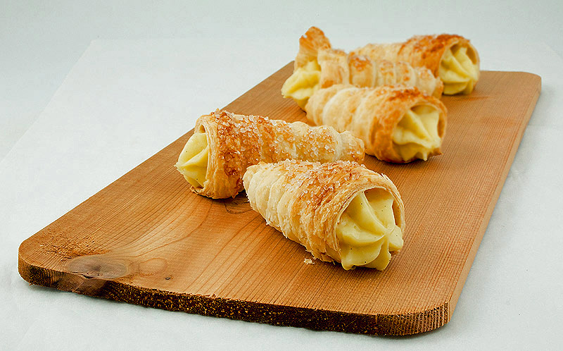 Italian Desserts A photo of Italian Desserts, Cannoncini alla Crema Pasticcera displayed on a cedar plank.