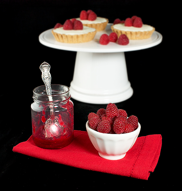 White Chocolate Raspberry Tarts A photo of White Chocolate Raspberry Tarts displayed with Raspberry Jam and a bow of fresh Raspberries.