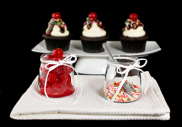 Dark Chocolate Cupcakes A photo of Dark Chocolate Cupcakes decorated to resemble Hot Fudge Sundaes, displayed with maraschino cherries and rainbow nonpareils.