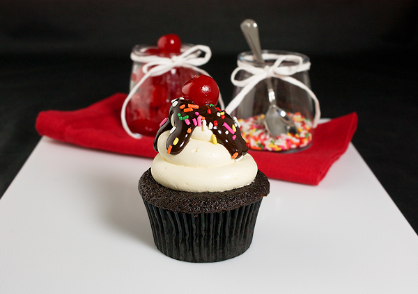 Chocolate Cupcakes with Vanilla Frosting A photo of a Chocolate Cupcakes with Vanilla Frosting decorated to resemble a Hot Fudge Sundae with Chocolate Ganache, rainbow sprinkles and a maraschino cherry.