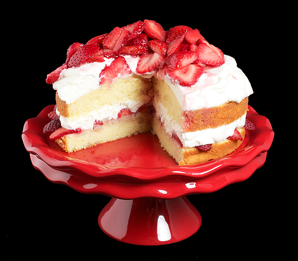strawberry cake, strawberry recipes, strawberry shortcake pictures A photo of Strawberries and Cream Cake on a red cake stand, displayed with a slice removed.