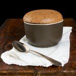 Soufflè di Nutella - Nutella Soufflé A photo of a Nutella Soufflé dessert, served in a brown ramekin and placed on a white napkin with a dessert spoon.