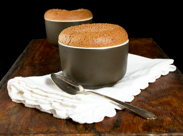 chocolate souffle recipes, chocolate desserts, recipe chocolate souffle A photo of two Chocolate Souffles in brown ramekins set on a dark wooden board with dessert spoons and a white napkin.
