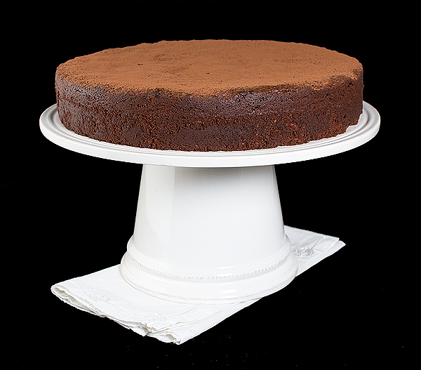La Torta Caprese A photo of Italian Cake, La Torta Caprese, dusted with cocoa and displayed on a cake stand.