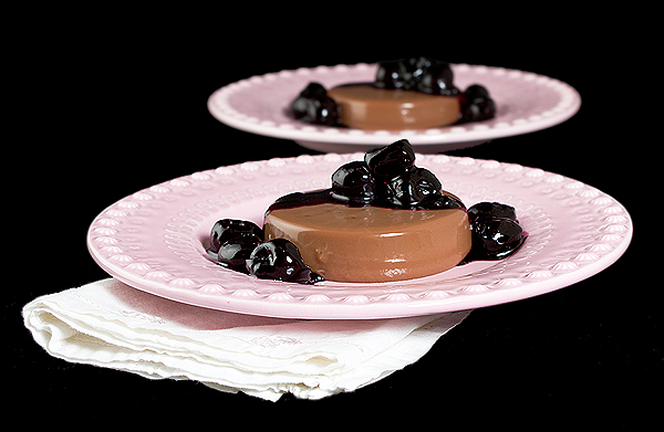 Milk Chocolate Panna Cotta with Port Cherry Sauce A photo of two Italian Desserts, Milk Chocolate Panna Cotta with Port Cherry Sauce served on pink dessert dishes.
