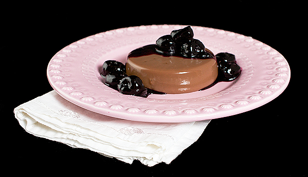 Italian dessert recipes, recipes for Italian desserts, easy Italian desserts A photo of an Italian Dessert, Chocolate Panna Cotta with Port Cherry Sauce served on a pink dessert dish placed on top of a white cloth napkin.