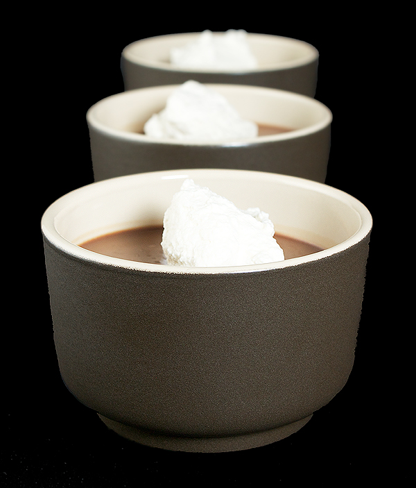chocolate panna cotta, cherry sauce, Italian Desserts A photo of three Chocolate Panna Cotta Italian Desserts served with a dollop of Sweetened Whipped Cream in brown dessert cups arranged in a row, one behind the other.