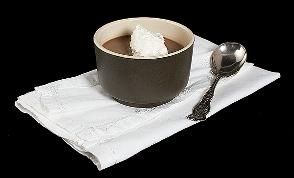dessert sauce, sauces recipes, chocolate dessert recipes, best dessert recipes A photo of an Italian Chocolate Dessert, Milk Chocolate Panna Cotta served with a dollop of Sweetened Whipped Cream in a ramekin placed on a white cloth napkin with a antique dessert spoon.