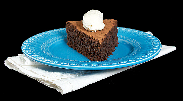 Italian Desserts A photo of an Italian Dessert, a slice of Torta Caprese o a blue dessert dish, topped with a quenelle of Sweetened Whipped Cream.
