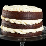 Red Velvet Cake with Raspberry Filling and Cream Cheese Frosting A photo of a Red Velvet Cake layered with Raspberry Filling and Cream Cheese Frosting displayed on a glass cake stand.