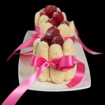 Charlotte con Mousse di Cioccolato Bianco e Lamponi (White Chocolate and Raspberry Charlotte) A photo of three Italian Cakes, Charlotte con Mousse di Cioccolato Bianco e Lamponi on a white dish, displayed in a row one behind the other.