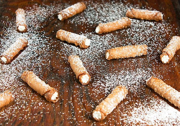 Mini Cannoli Siciliani A photo of Mini Cannoli Siciliani displayed on a dark wood board.