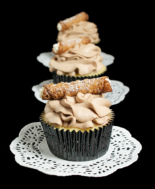 Cannoli Cupcakes A photo of 3 Cannoli Cupcakes placed in a row, one behind the other, decorated with tiny cannoli.