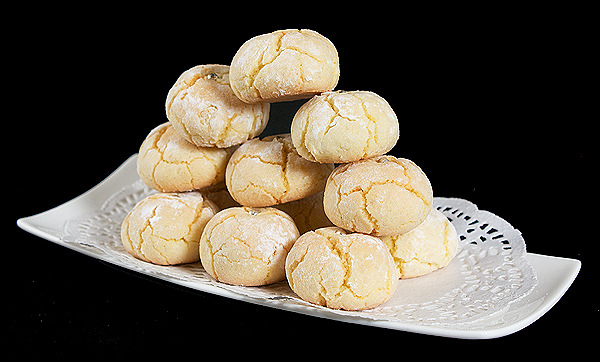 Italian cookies recipes, amaretti biscuits, amaretto cookies A photo of Amaretto Cookies stacked on a rectangular white dish lined with white doilies.