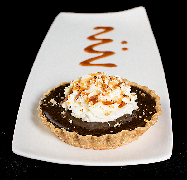 recipes for caramel, shortcrust pastry, shortcrust pastry recipes, chocolate glaze A photo of a Chocolate Caramel Tart on a white dessert dish with a decorative drizzle of caramel sauce on the dish.