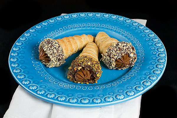 Italian Pastry Desserts A photo of Italian Pastries, Cannoncini di Sfoglia con Crema Pasticcera al Cioccolato, dipped in chocolate and rolled in toasted hazelnuts, pistachios and almonds.