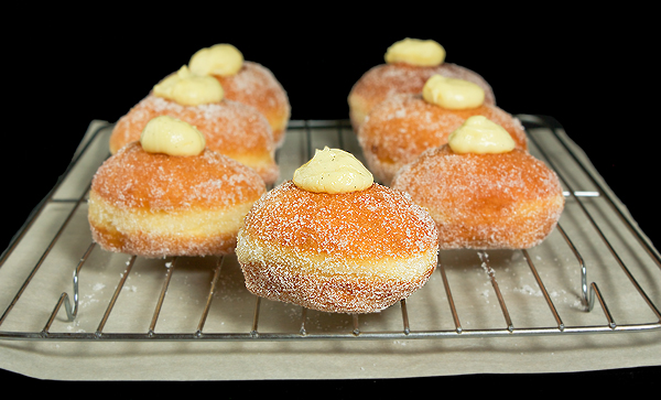 Bomboloni alla Crema - Krapfen {Italian Cream-Filled Donuts} A photo of Italian Cream-Filled Doughnuts, Bomboloni alla Crema displayed on a wire cooling rack.