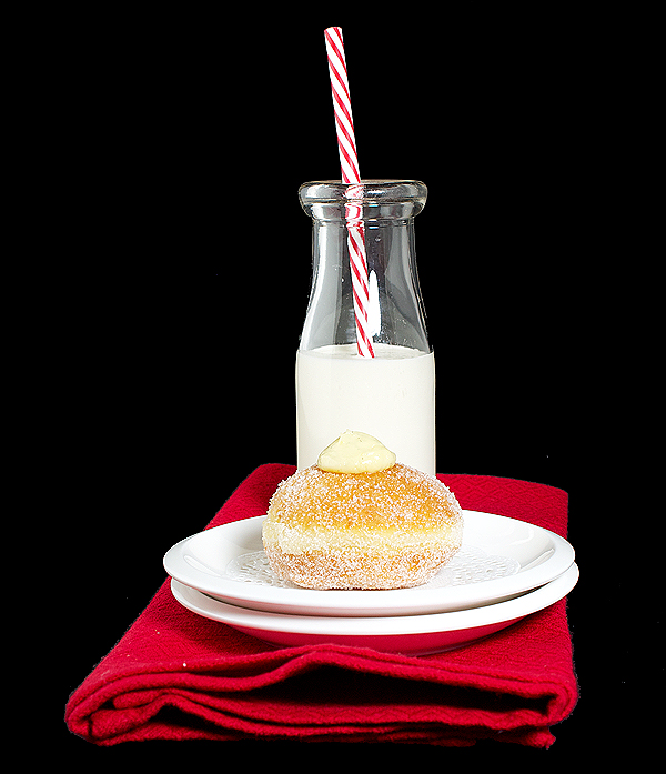 Berliner, Bomboloni A photo of an Italian Pastry, Bomboloni also referred to as a Berliner displayed on a red cloth napkin with a glass of milk.